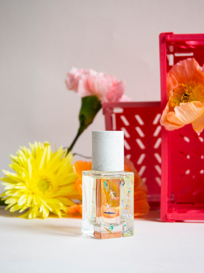 Bain de Midi eau de parfum bottle with clear glass, frosted cap, and colorful label artwork