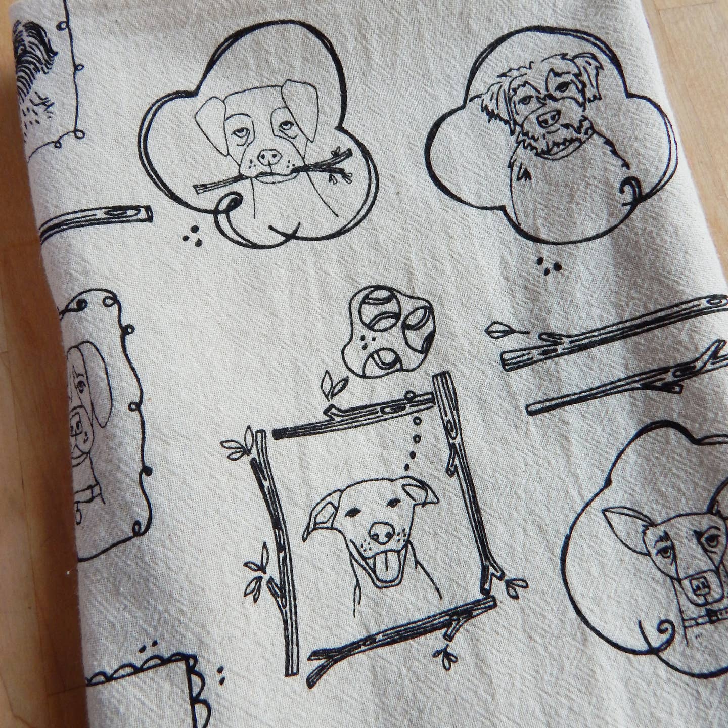 Dog kitchen tea towel close-up with large line-drawn cloud dog faces and chopsticks.
