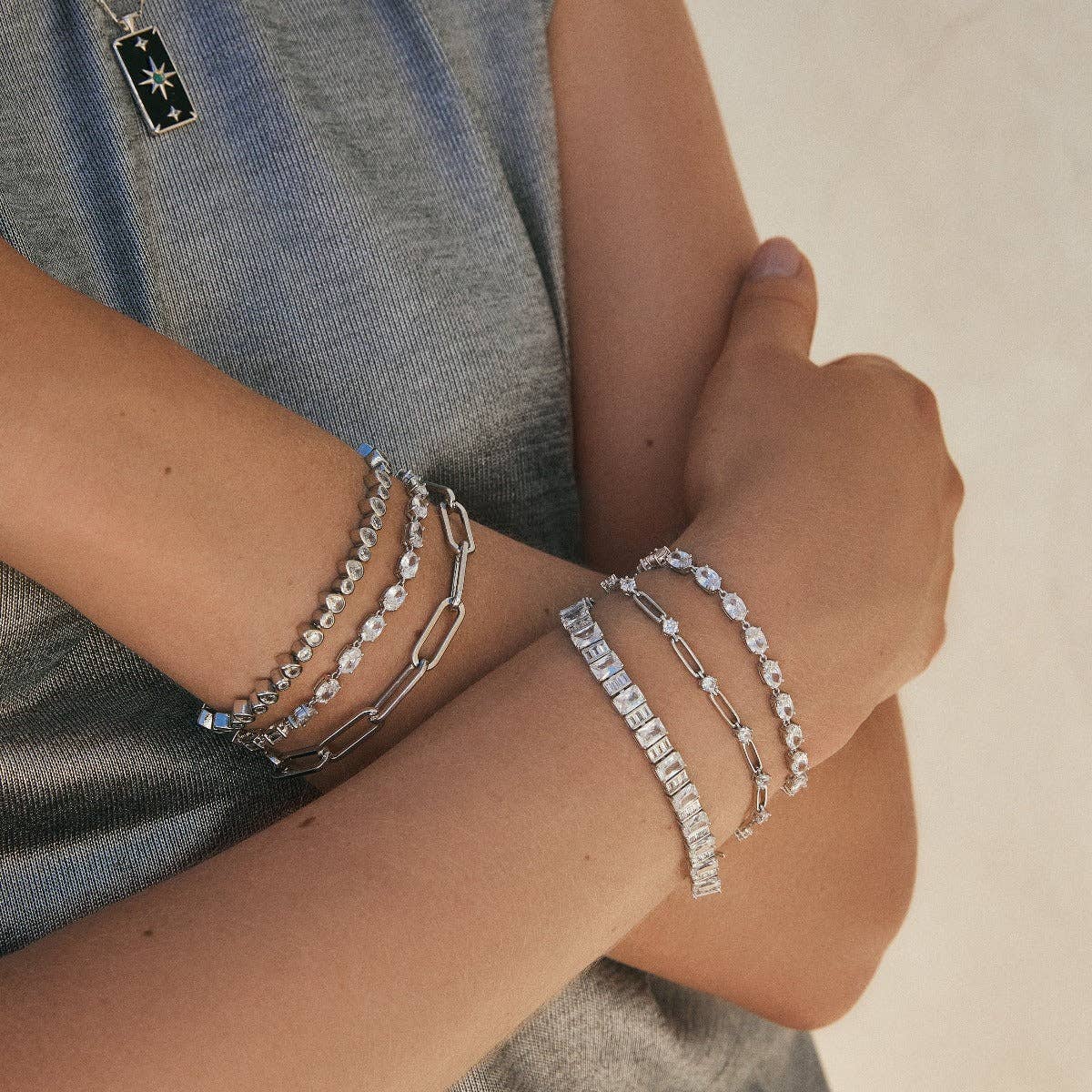 Oval tennis bracelet with rhodium silver oval crystal links on wrist, secured by a box clasp