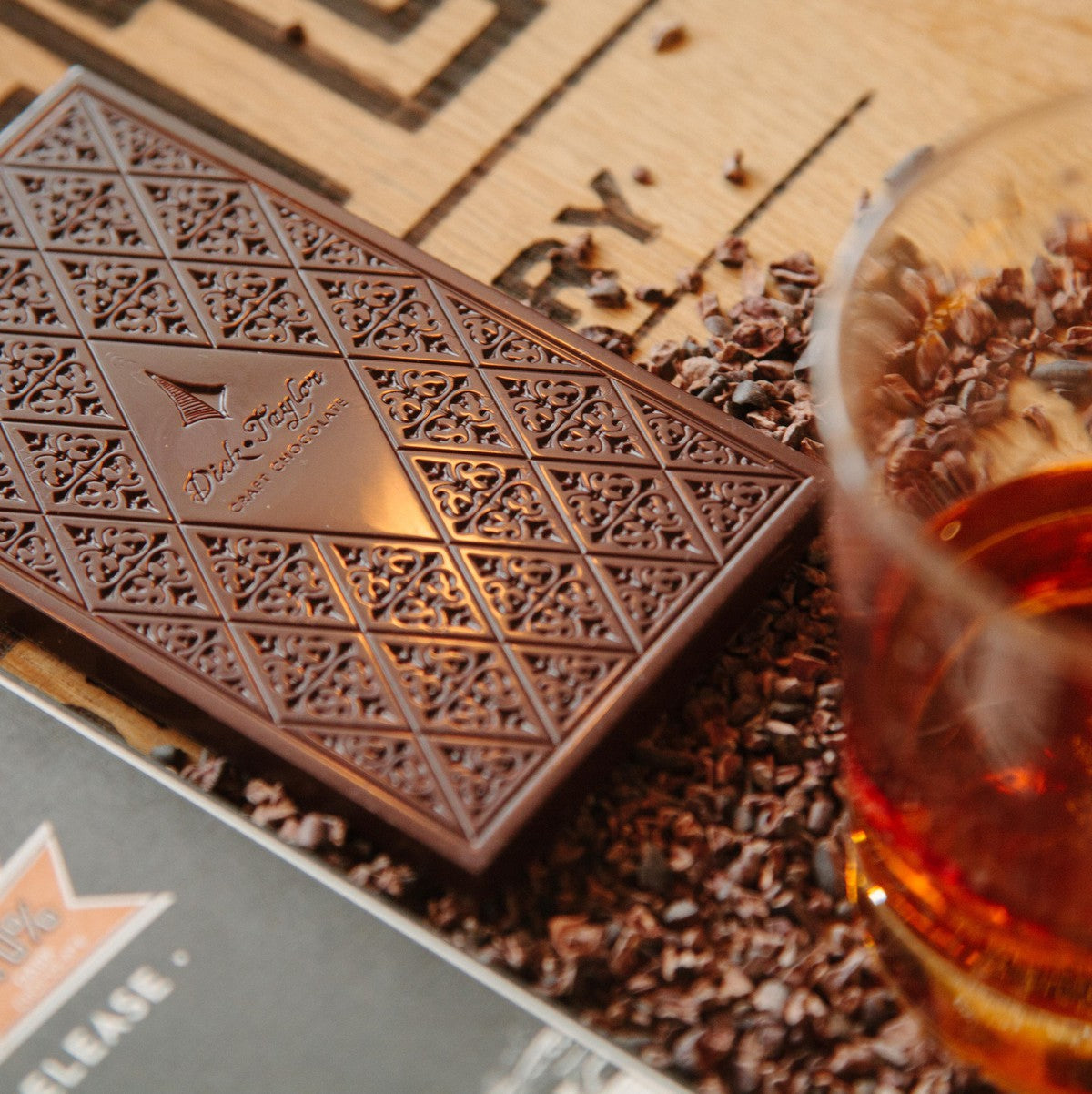 Embossed dark chocolate slab with ornate pattern, scattered cocoa bits nearby