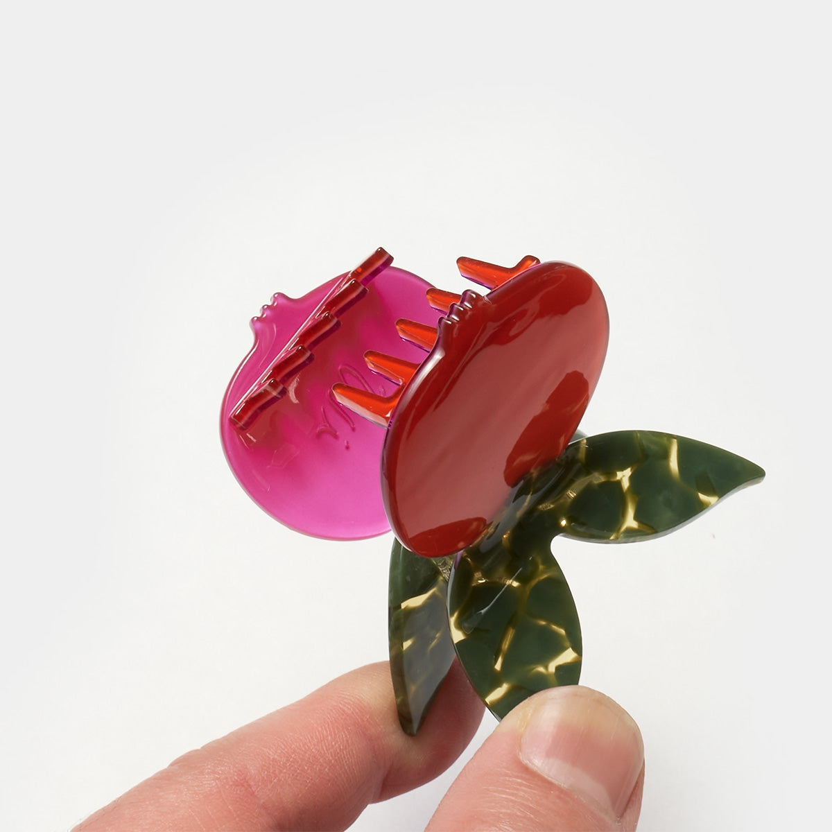 Butterfly hair claw close-up: glossy red pomegranate, green wings, purple clip