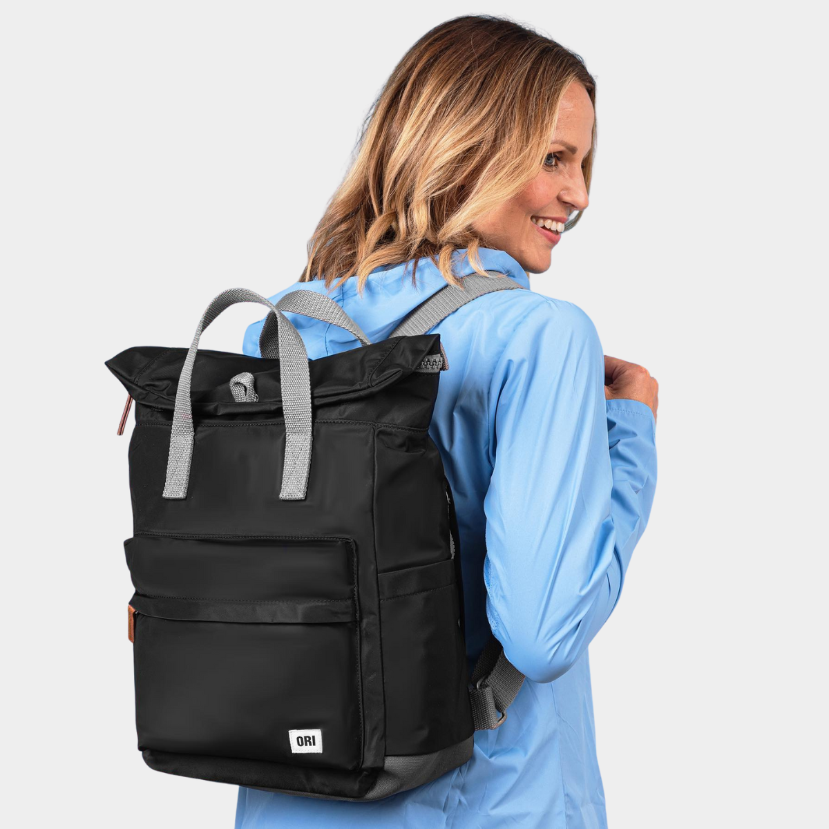 Black medium nylon backpack with padded straps and top handle, shown worn on model