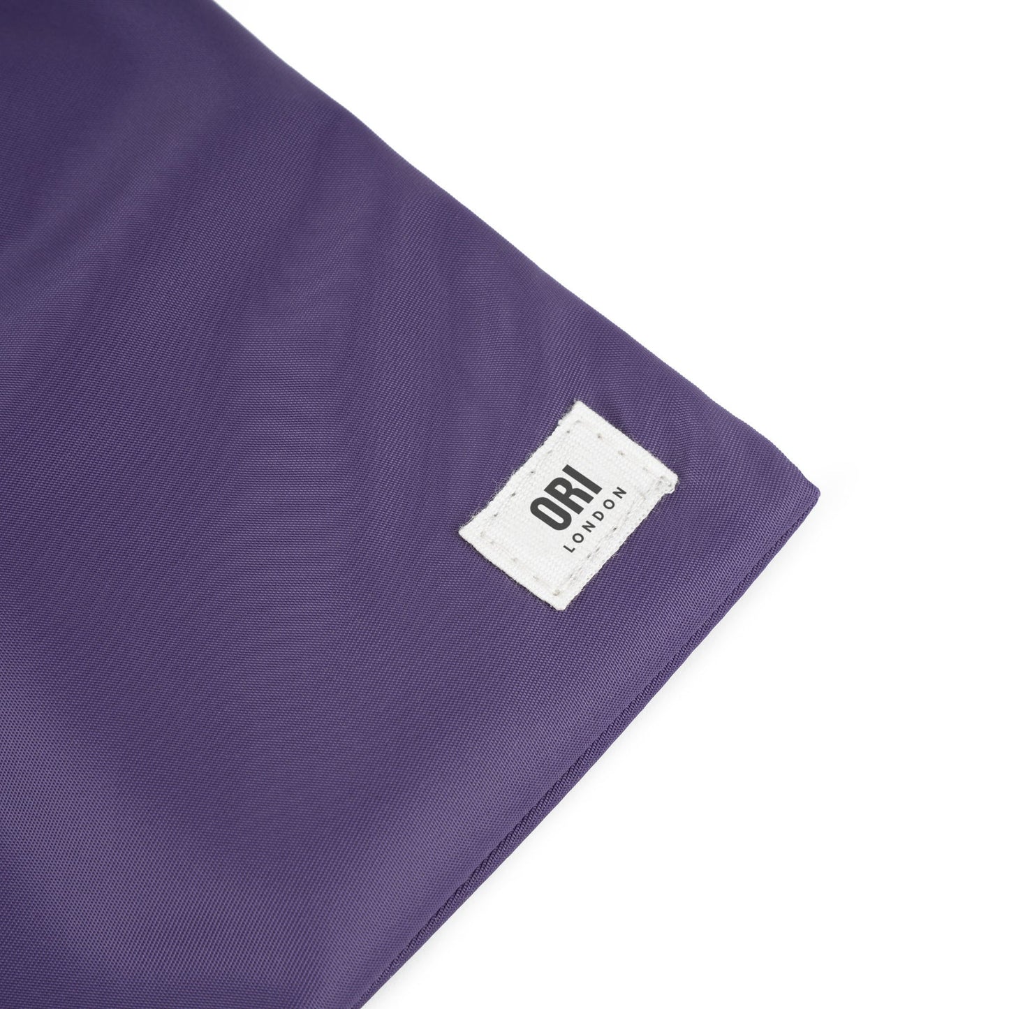 Close-up of purple recycled nylon pocket crossbody label and fabric texture
