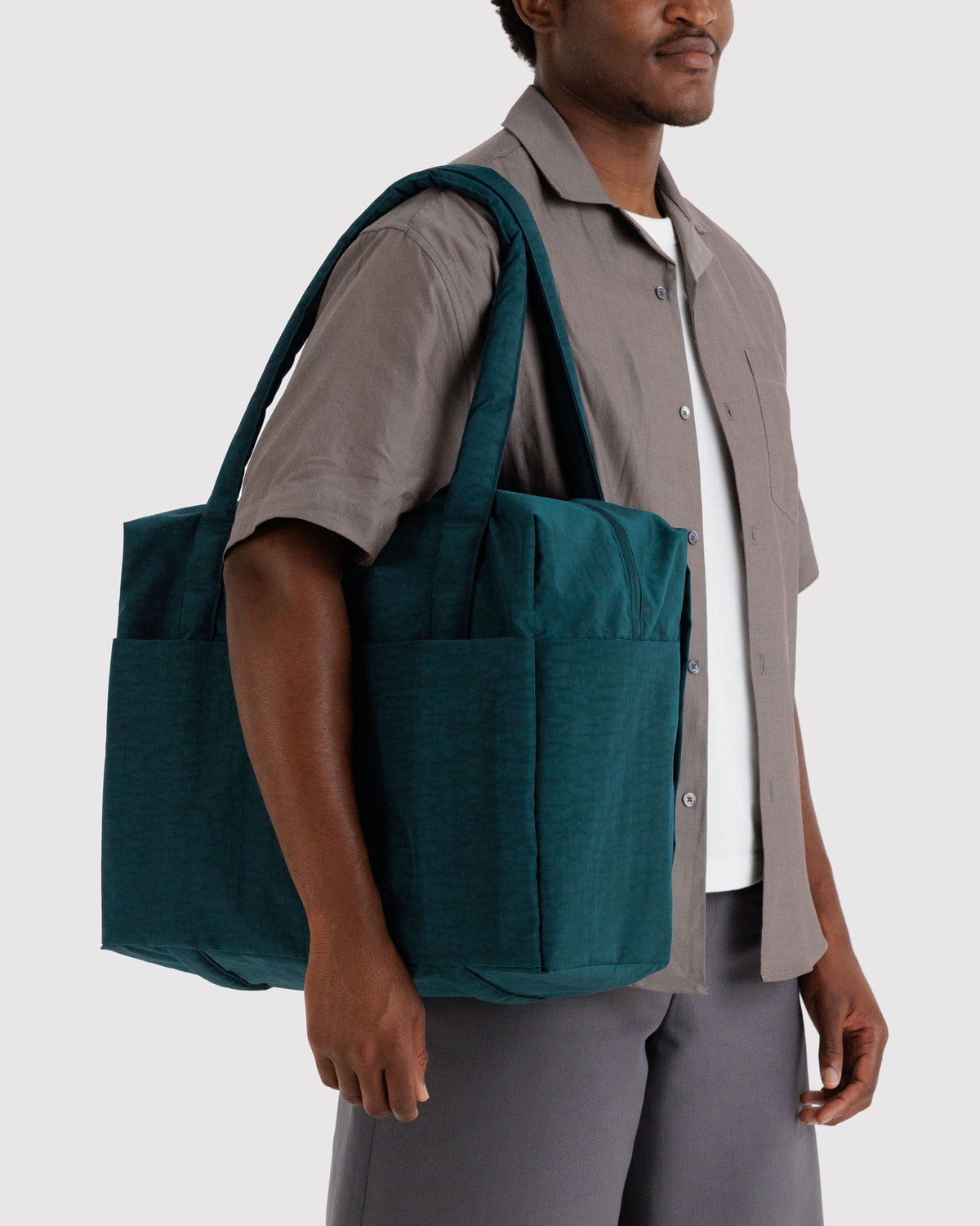 Carry-on travel bag in teal with interior compartments and side pockets, worn by model.