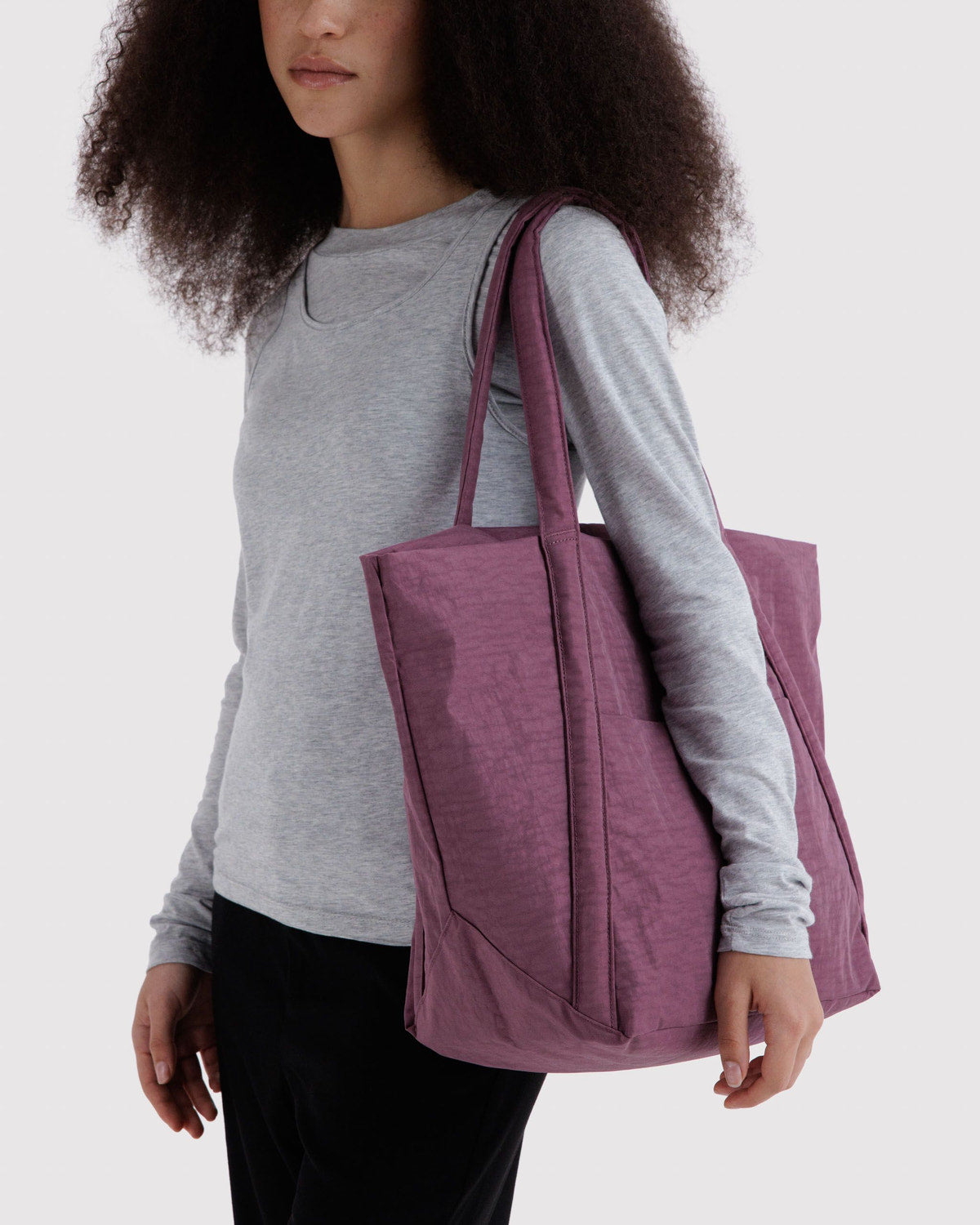 Plum tote bag carried on shoulder with two top handles and a roomy interior.