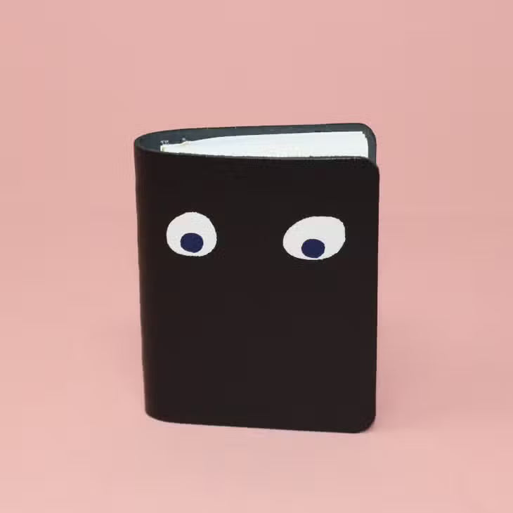 Black mini leather notebook with white googly eyes on the cover