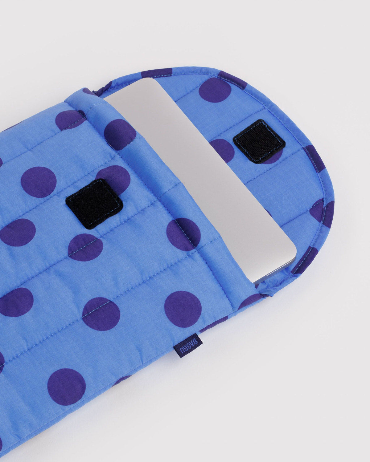 Blue puffy 13"/14" laptop sleeve with purple dots, quilted padding, and black label tabs.
