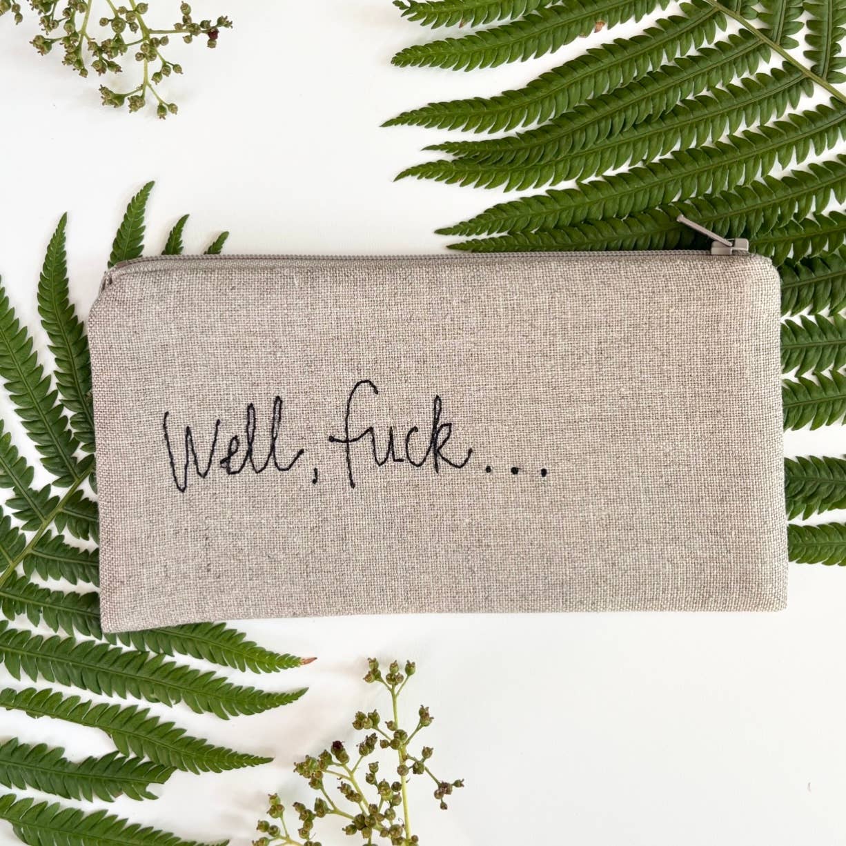 Beige linen zip pouch with 'Well, Fuck...' script on front