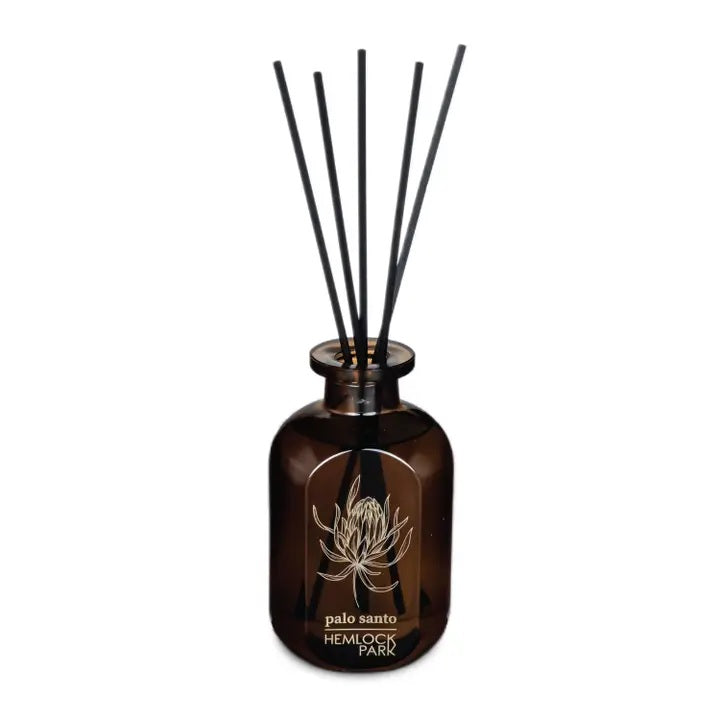 Amber glass reed diffuser jar with black reeds; palo santo scent label