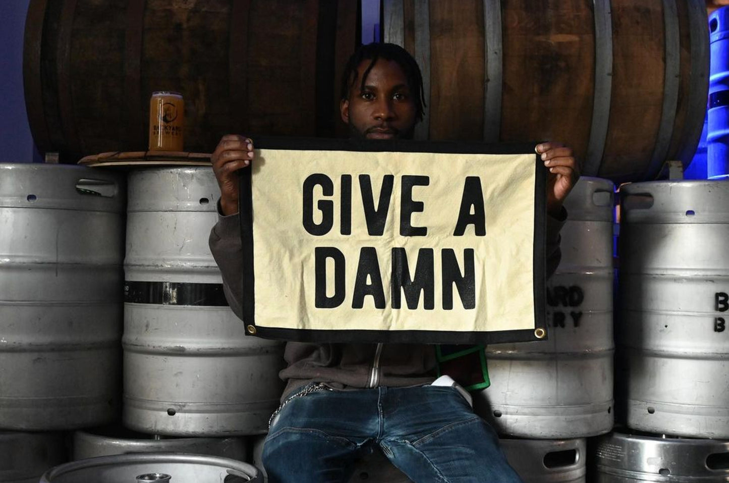 Person holding camp flag showing “GIVE A DAMN” text on light background