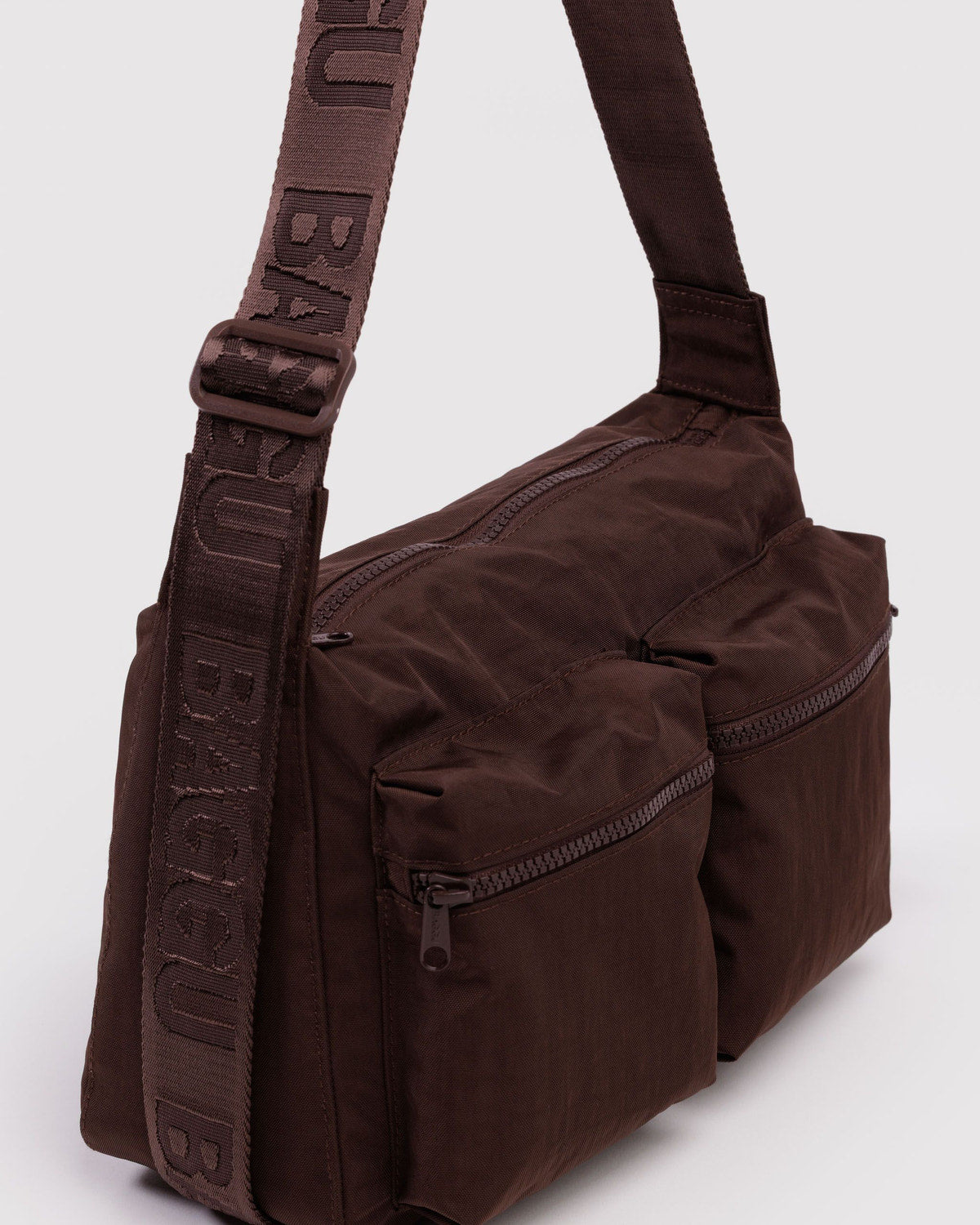 Brown medium cargo crossbody bag side view with zip pocket detail and webbed strap.