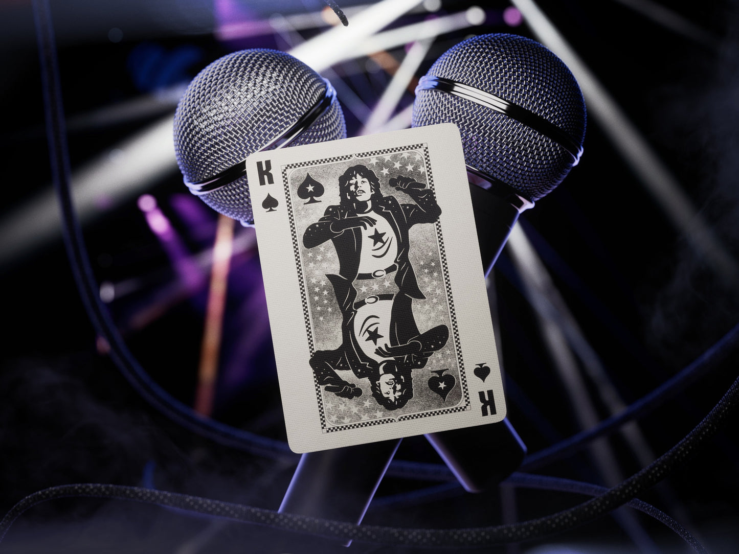 Playing card with black silhouette artwork and K label, held before microphones