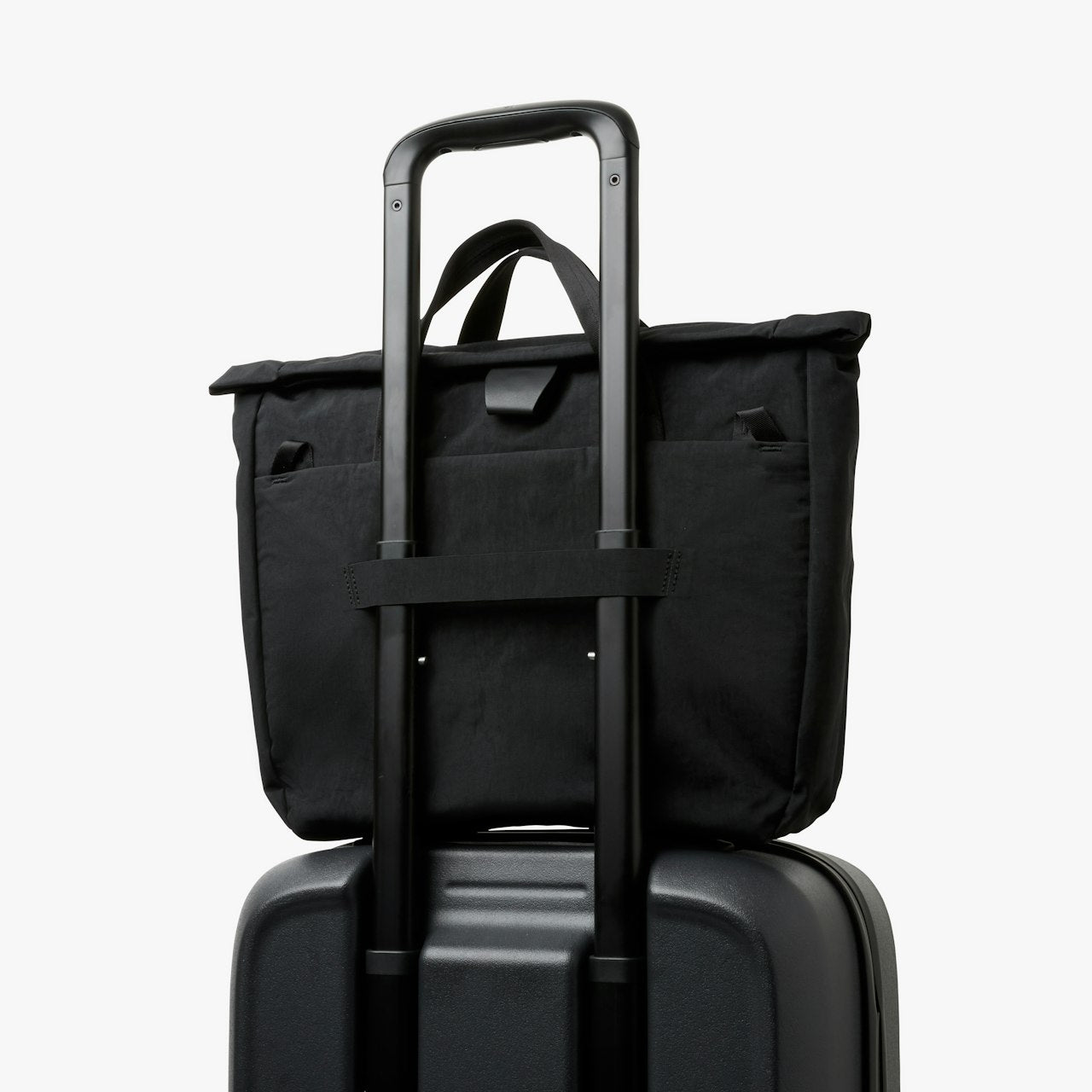 Black tote messenger bag with reinforced top and carry handle for stacking.