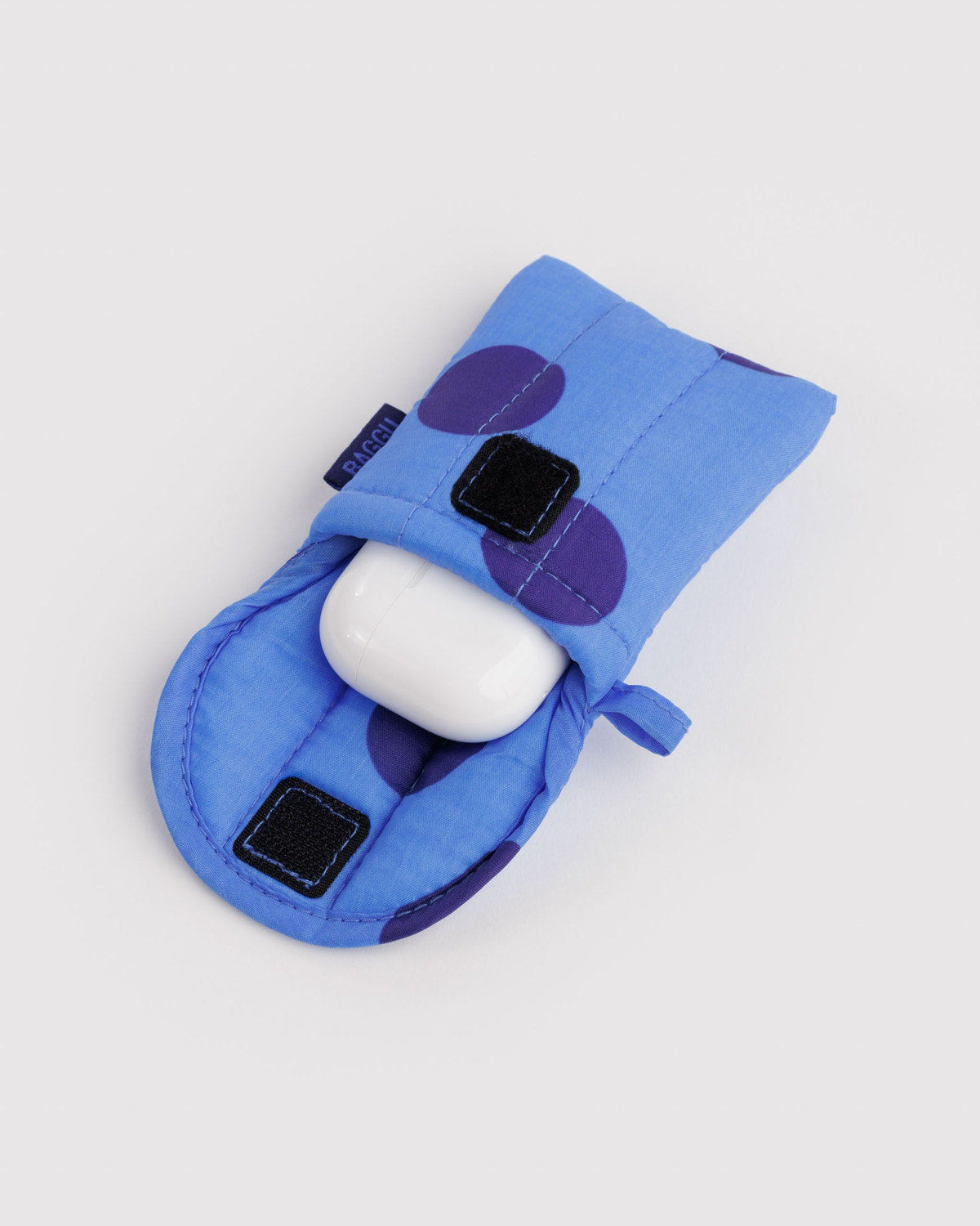 Puffy earbuds case in blue fabric with purple circles and black square patches, earbud inside