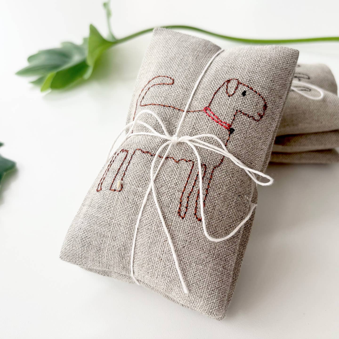 Gray dog-embroidered sachet pouch with white drawstring tie, folded with details visible