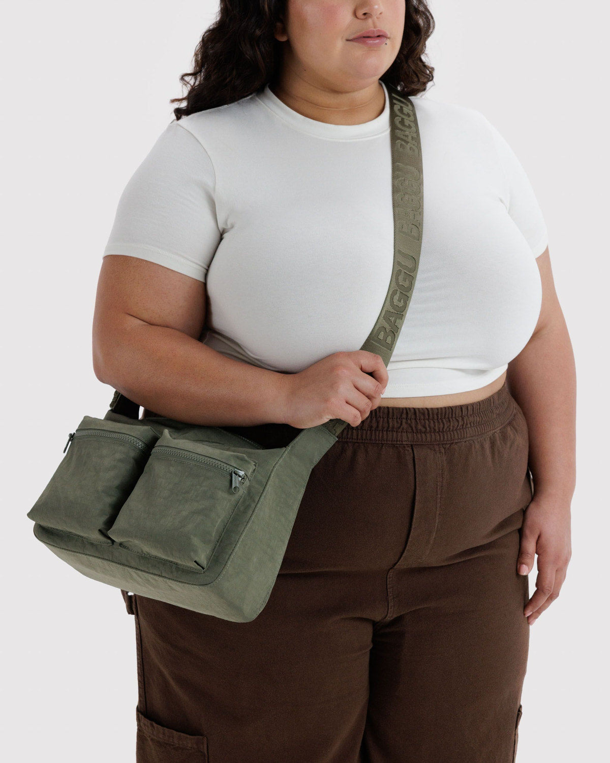 Olive green cargo crossbody bag worn across body, showing front zip pocket and strap.