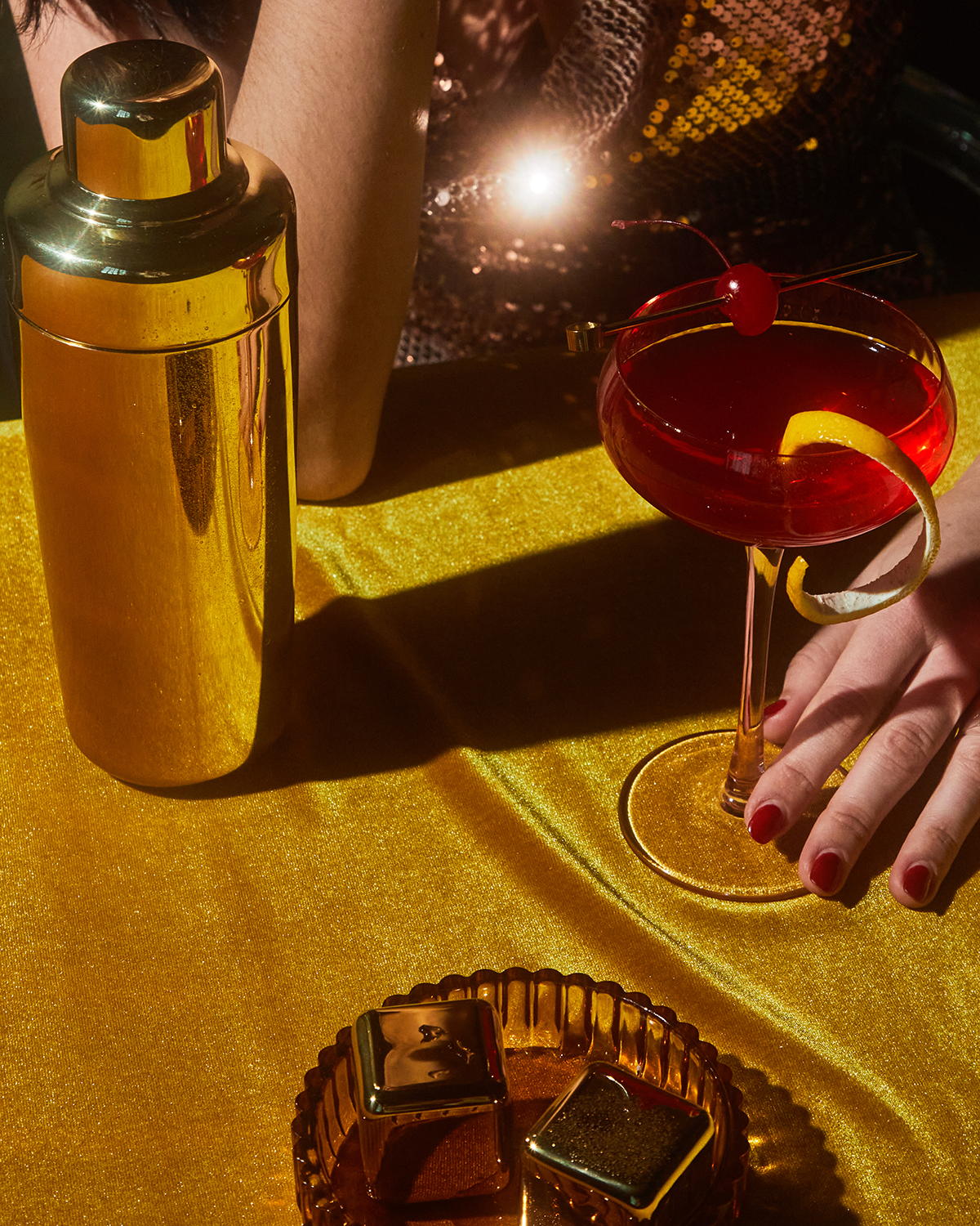Gold cocktail pick garnishing a cocktail glass with a red fruit topper
