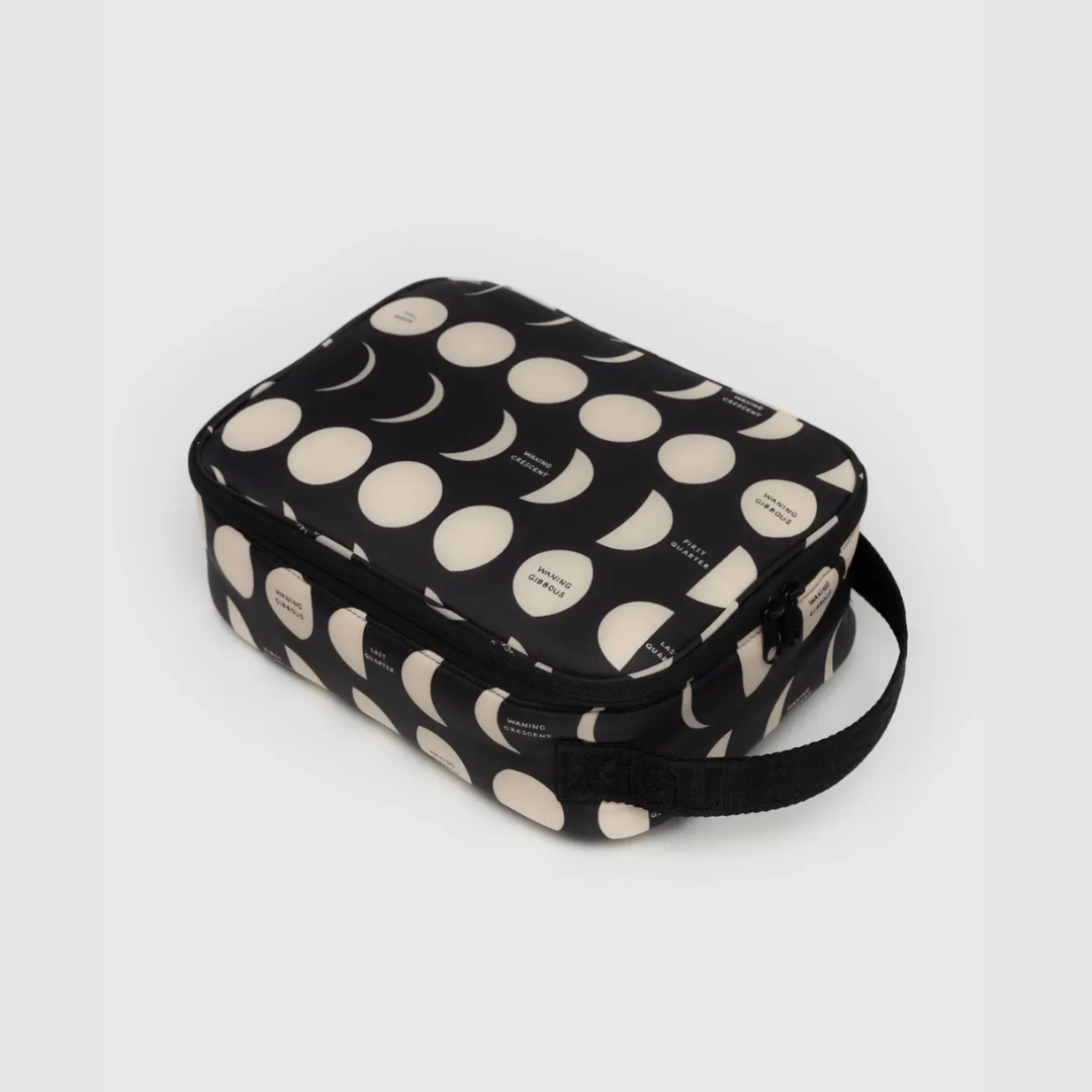 Black lunch bag with cream dot pattern, zipper closure and carry strap.