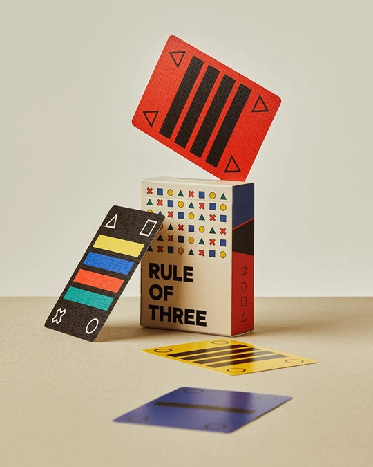 Playing card deck with red, blue, and black geometric card faces, cards scattered