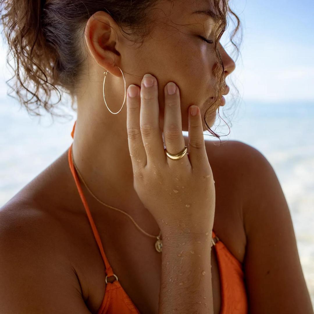 Gold vermeil wave ring worn on finger, smooth polished curved band.