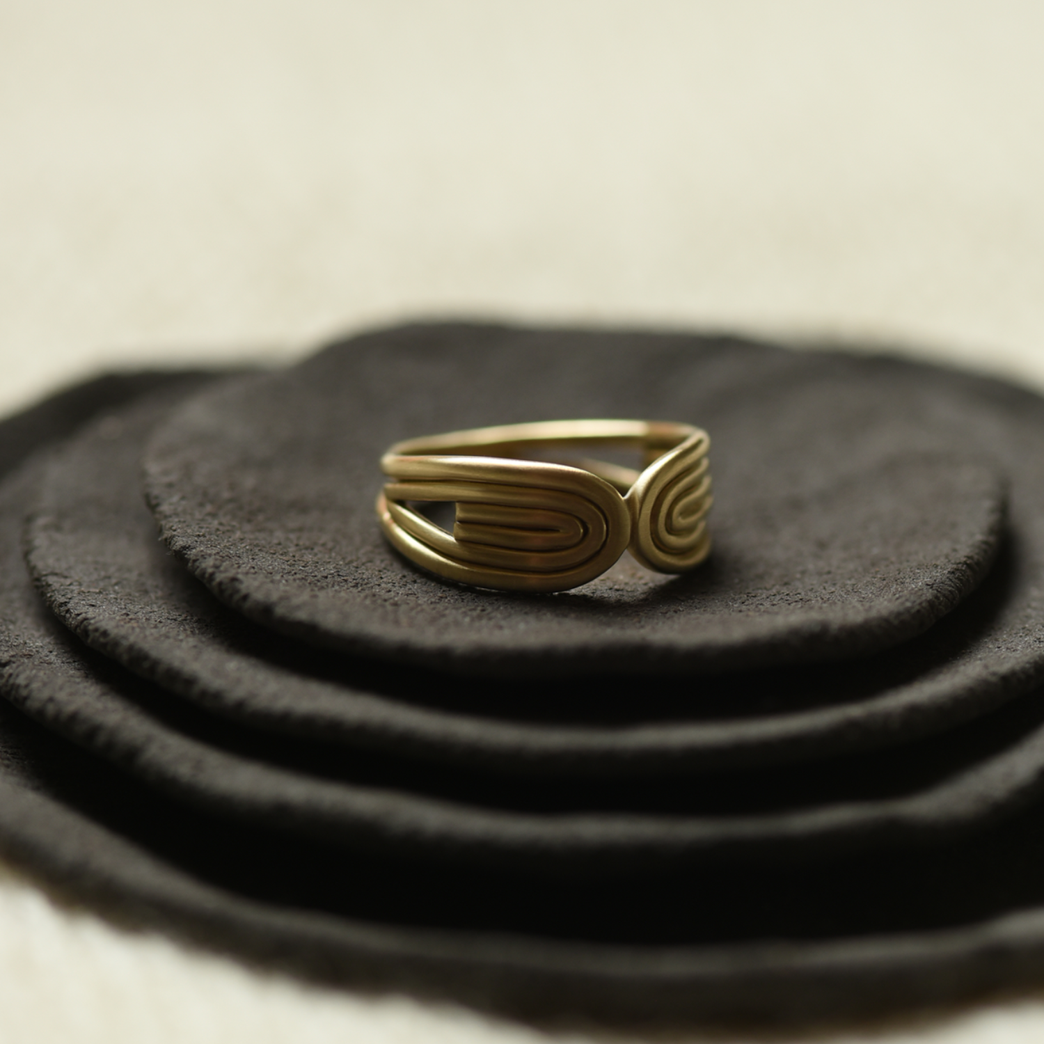 Gold sculpted double-arc ring with stacked oval arcs and spiral detail
