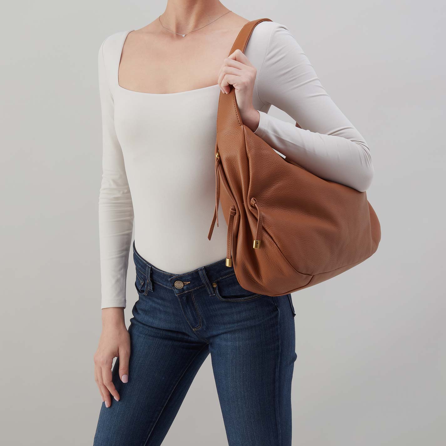 Warm honey hobo bag carried on shoulder with side ties and gold-tone hardware