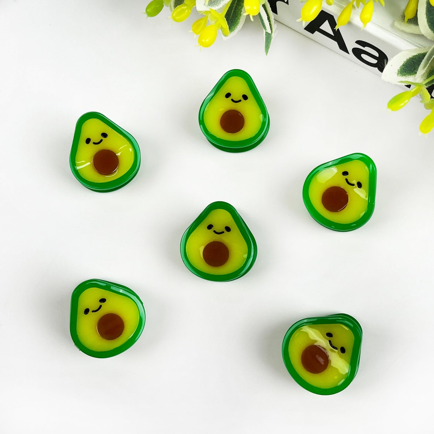 Avocado-shaped mini hair clips, multiple green-yellow faces with brown seed detail
