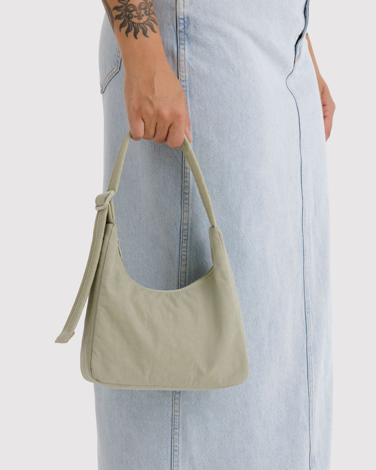 Mini nylon shoulder bag in sage green held by model with short handles