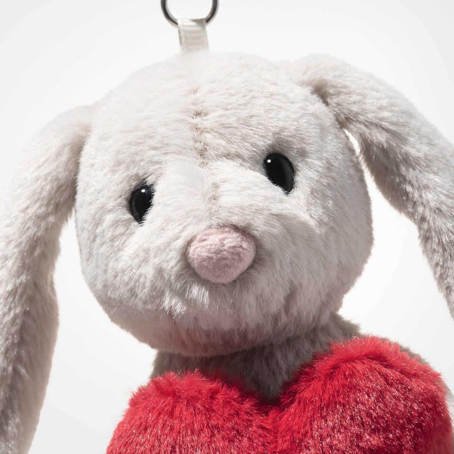 Rabbit plush keyring close-up: gray face, pink nose, and red heart chest
