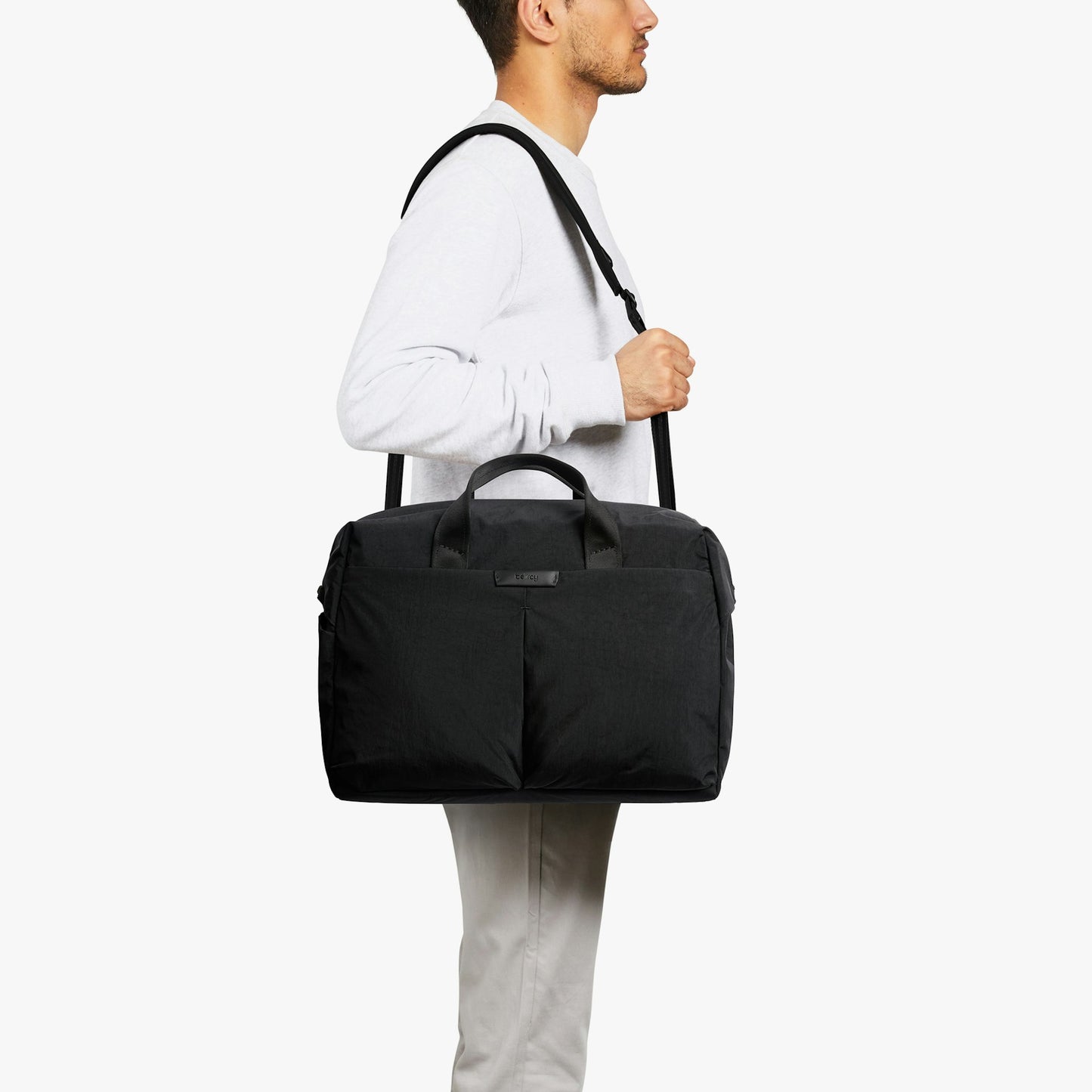 Black work bag worn on shoulder with top handles and front compartment