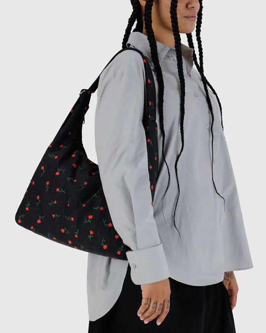 Black nylon shoulder bag with red floral print, shown hanging from shoulder