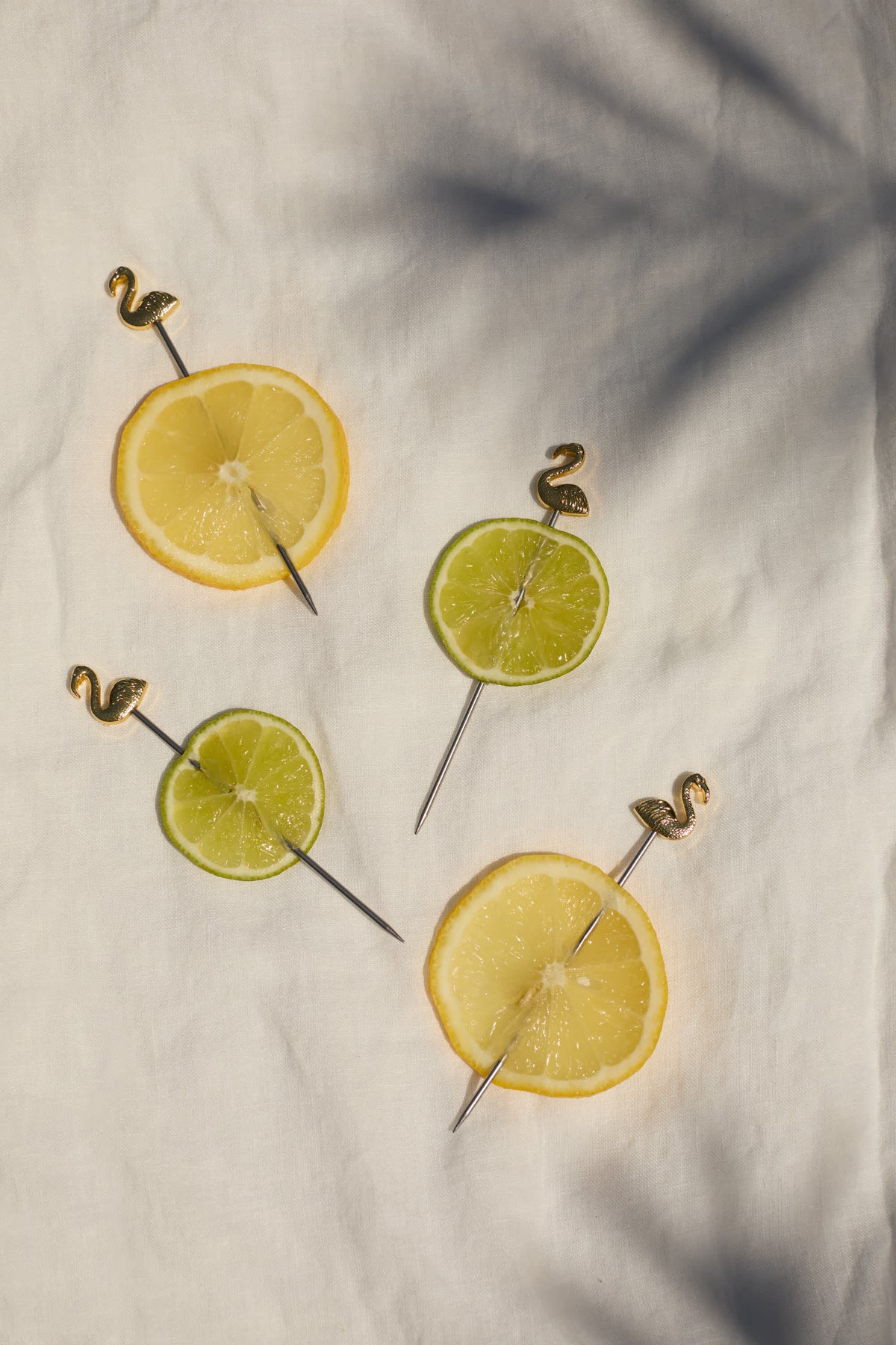 Lemon and lime slice cocktail picks with gold flamingo-style tips and metal stems