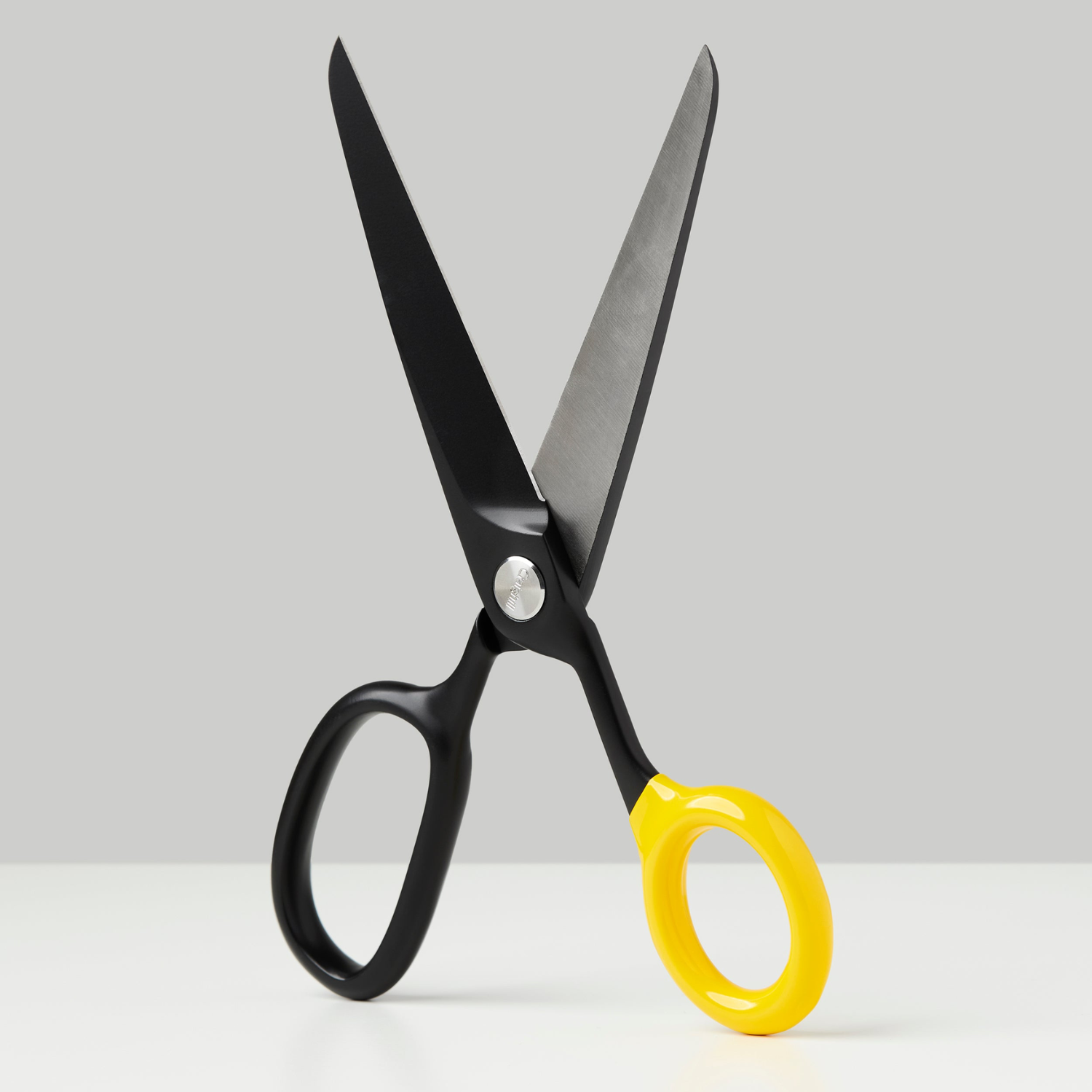 Black scissors with yellow finger rings, open blades and pivot screw