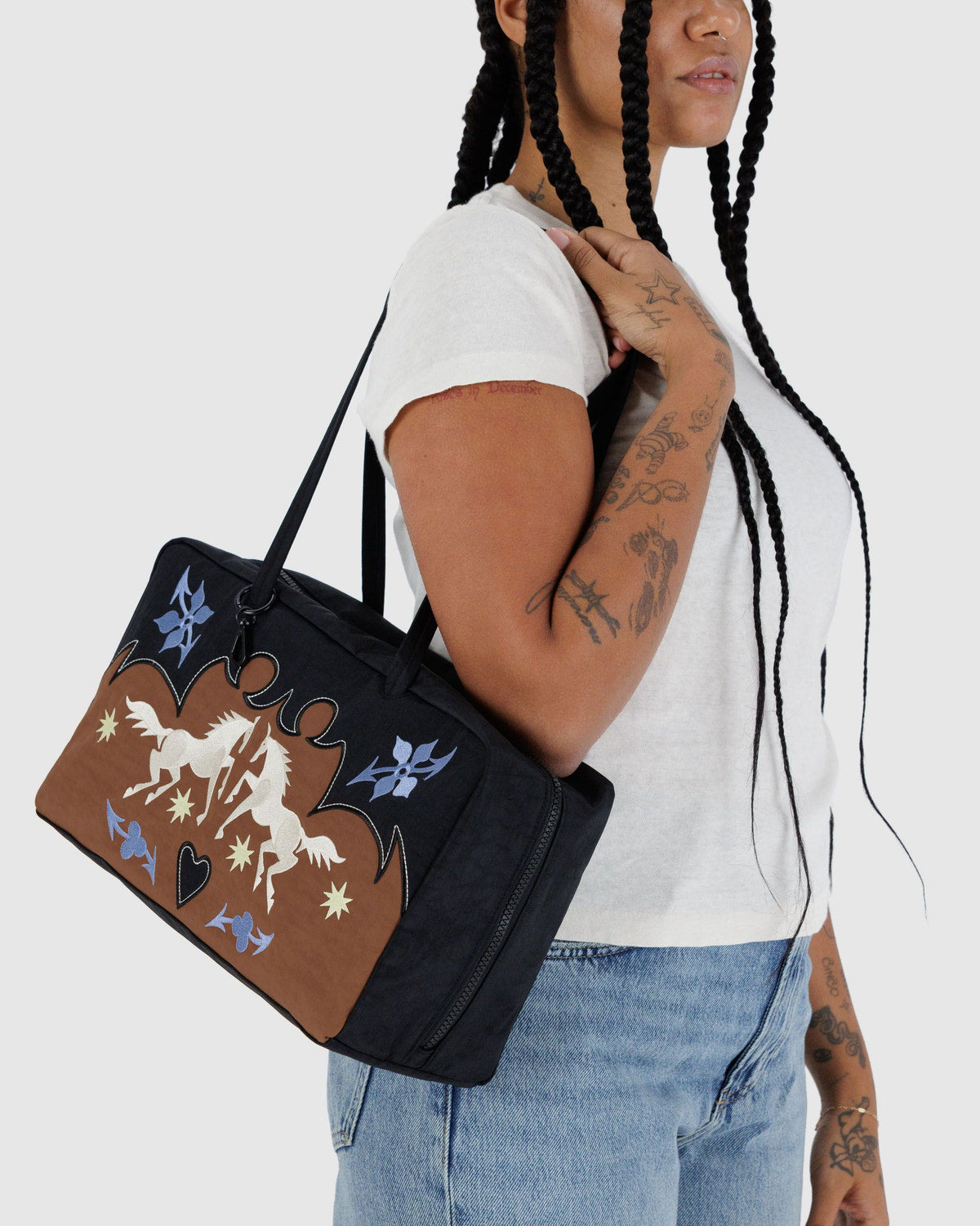 Medium nylon bowler bag held at side; black bag with brown front and illustrated design.