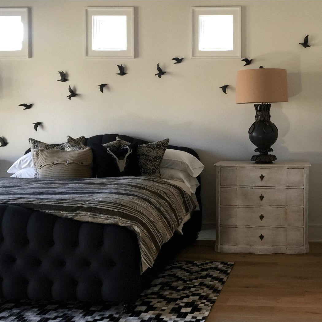 Black flying gull wall ornaments scattered around a bedroom bed and nightstand