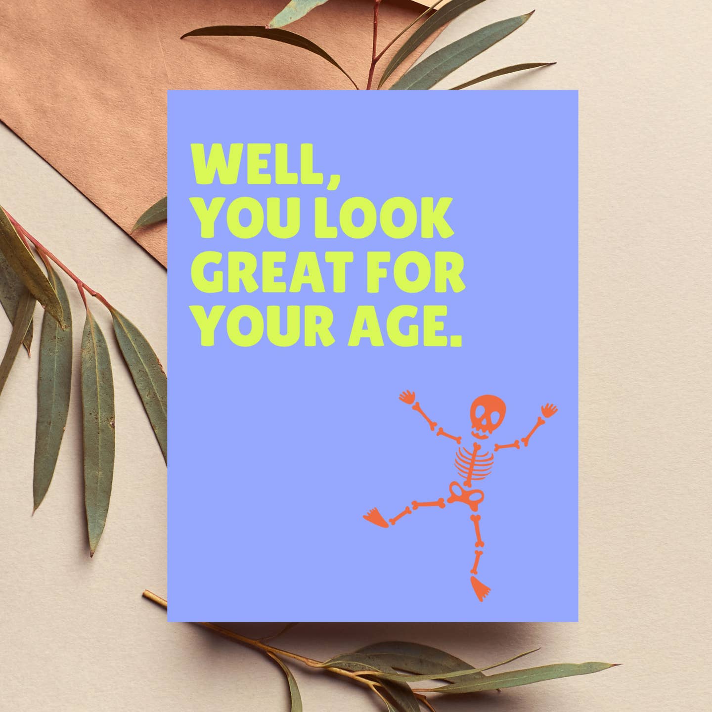 Blue greeting card with green text 'Well, you look great for your age' plus skeleton