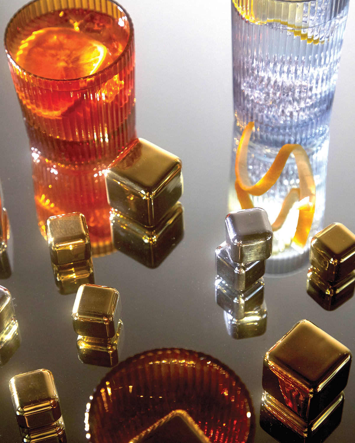 Set of gold square cocktail chiller cubes, clustered around drink glasses