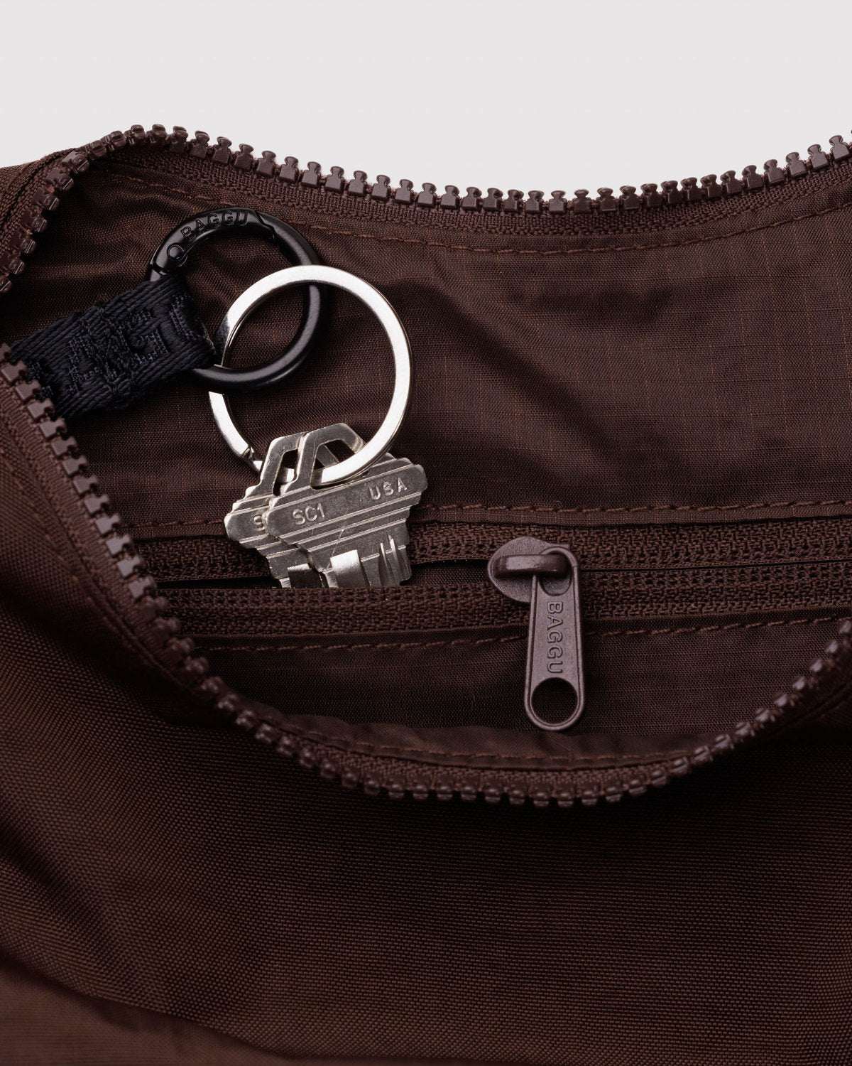 Small nylon crescent bag, brown interior close-up with key clip and zip