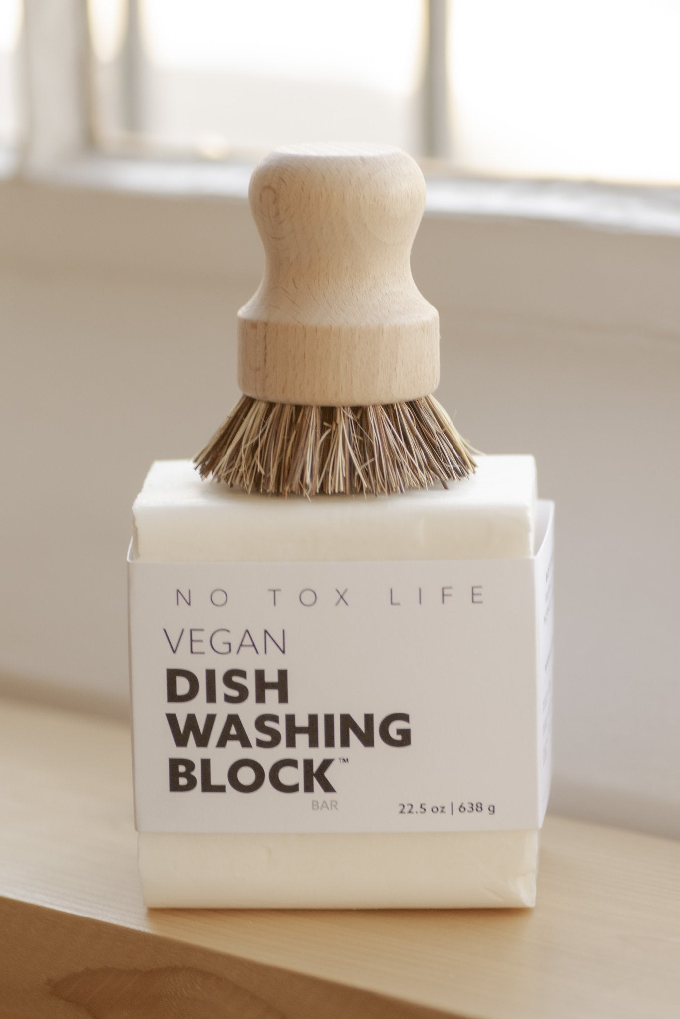 Large vegan dish washing block on sink with wooden brush and light bristles