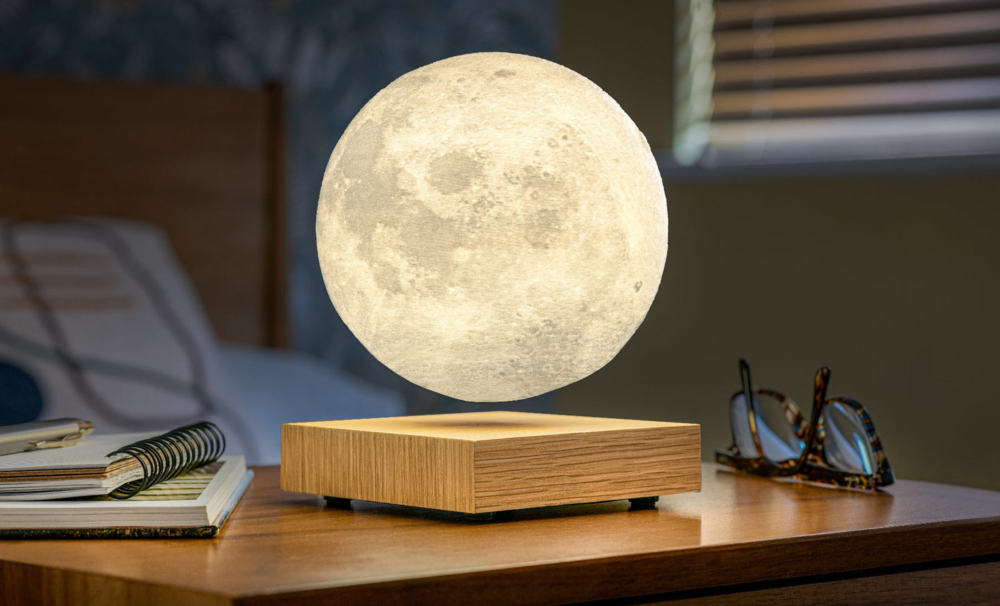 Moon-shaped lamp with glowing white sphere on light wood base