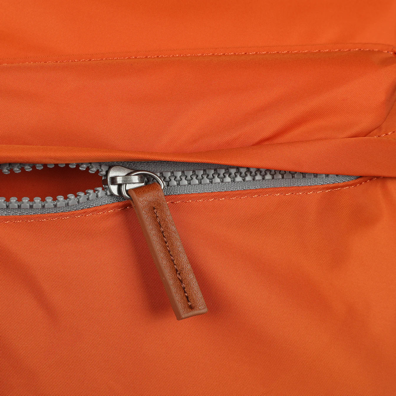 Orange nylon crossbody zipper with metal pull and brown leather tag