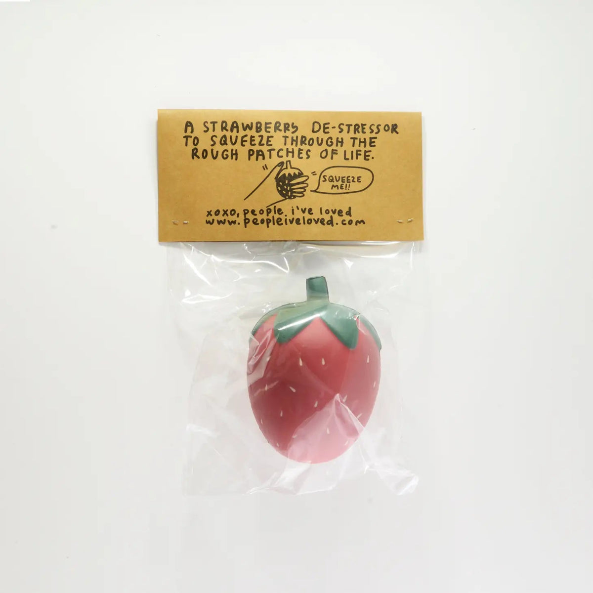 Strawberry stress ball with red fruit and green leafy top, in clear plastic bag