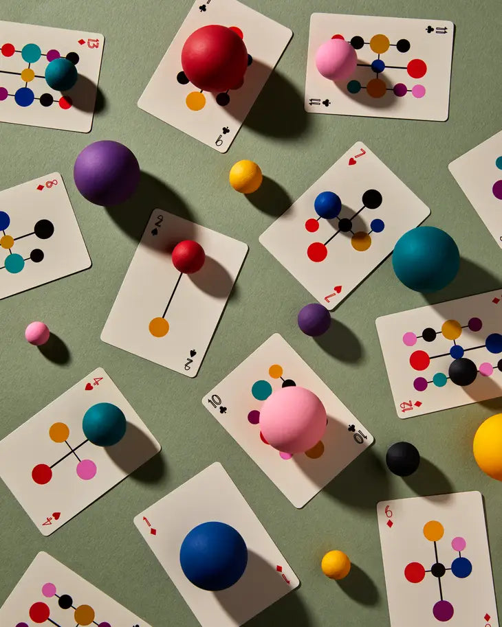 Assorted playing cards scattered with colorful atom-like circles and spheres
