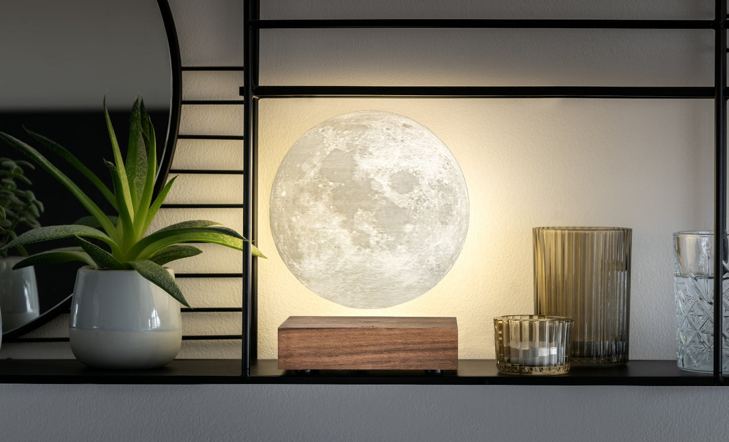 Moon-shaped lamp with glowing white sphere on wooden base, displayed on shelf