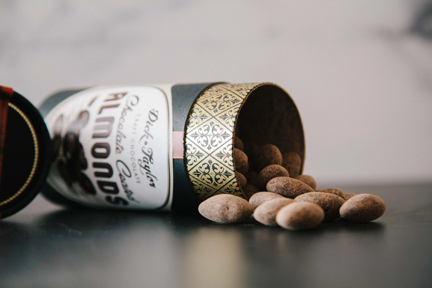 Chocolate-coated almonds scattered near bottle, dark cocoa-coated nuts