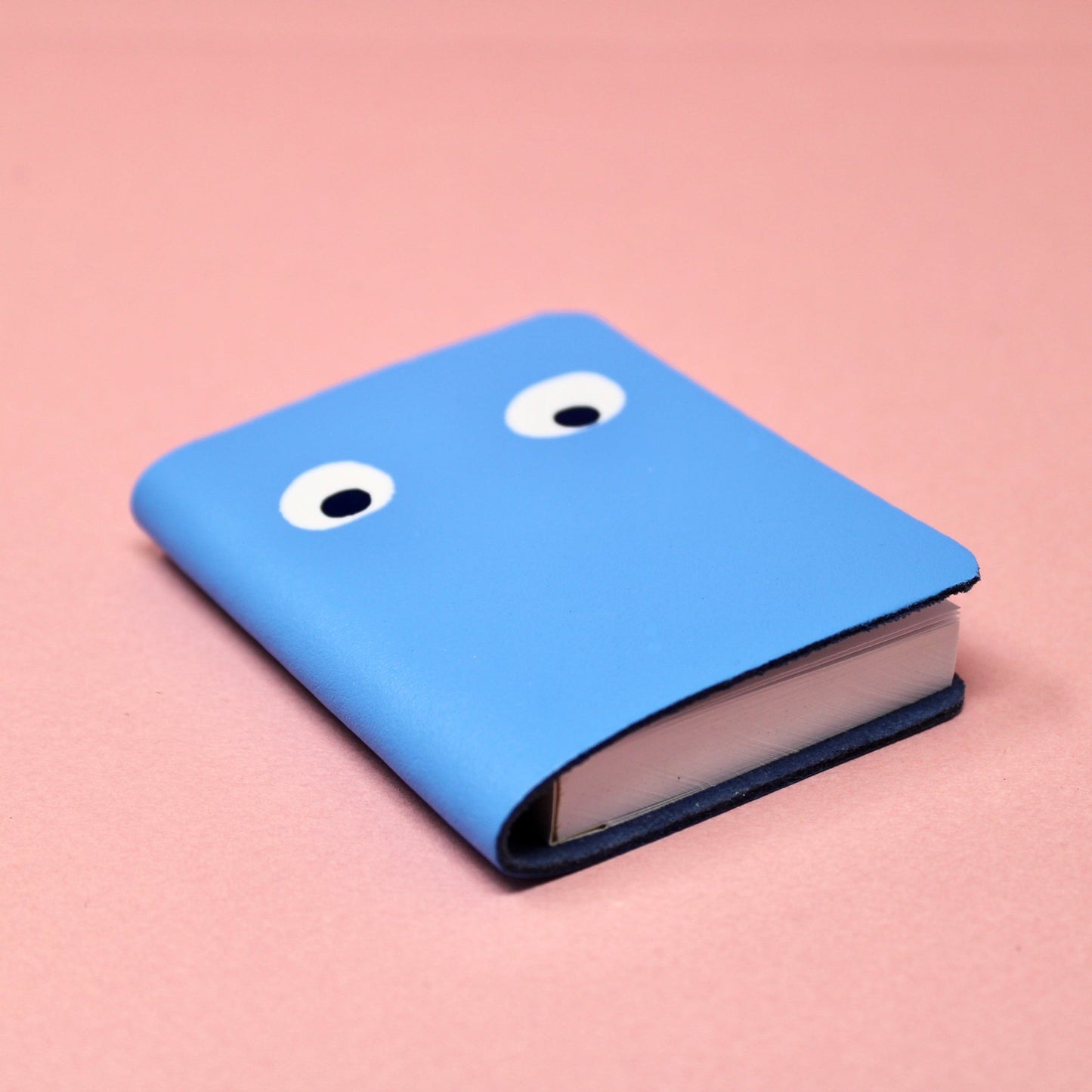 Blue mini leather notebook with white googly eyes printed on the cover