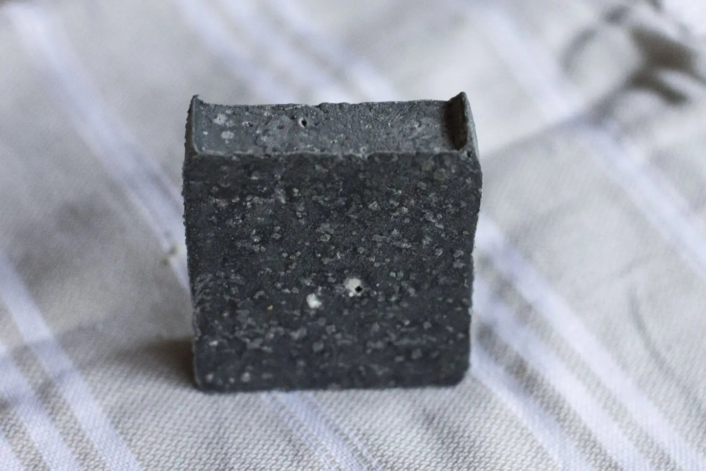 Charcoal gray square facial cleansing bar with speckled texture