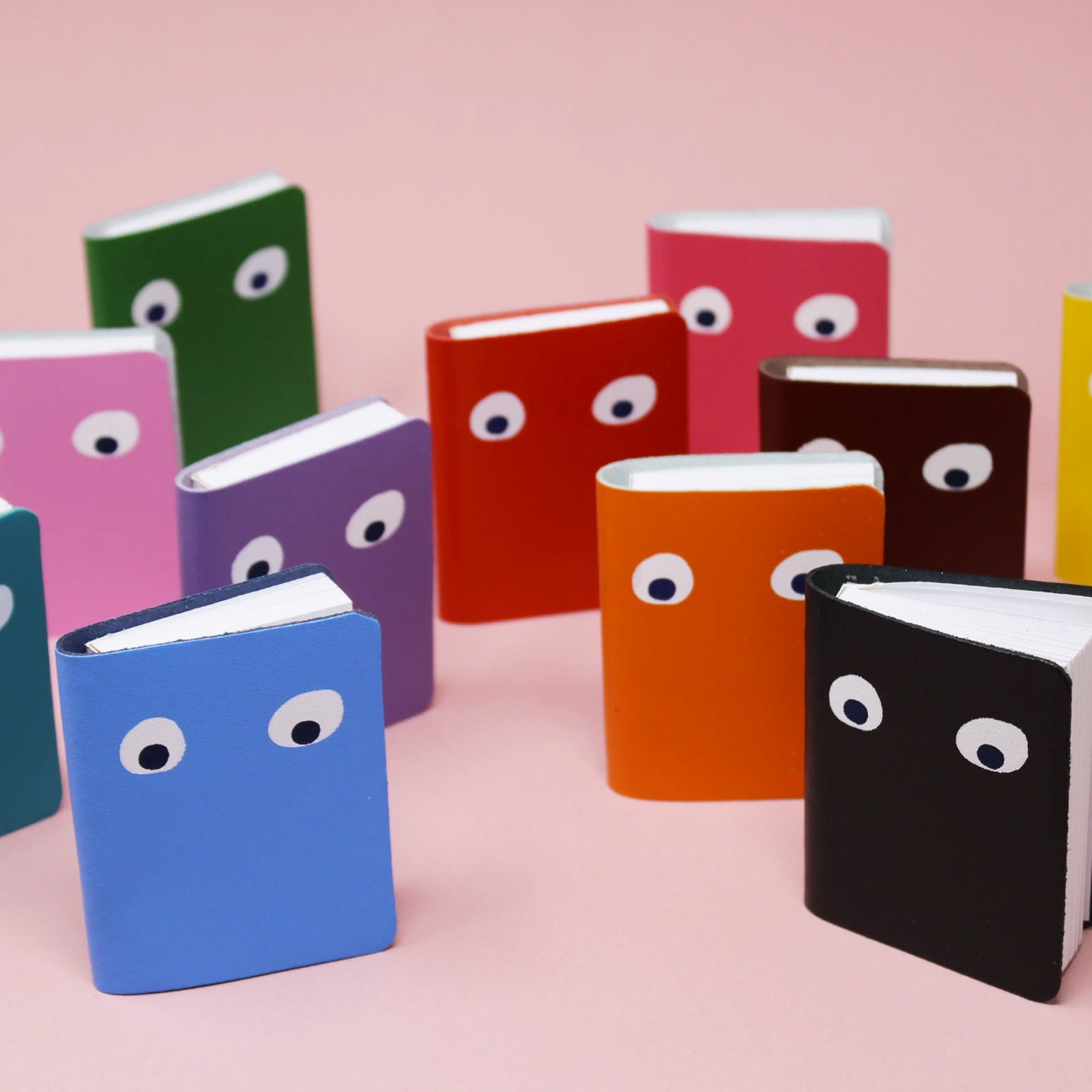 Googly eye mini leather notebooks, assorted colors with cartoon eye faces on covers