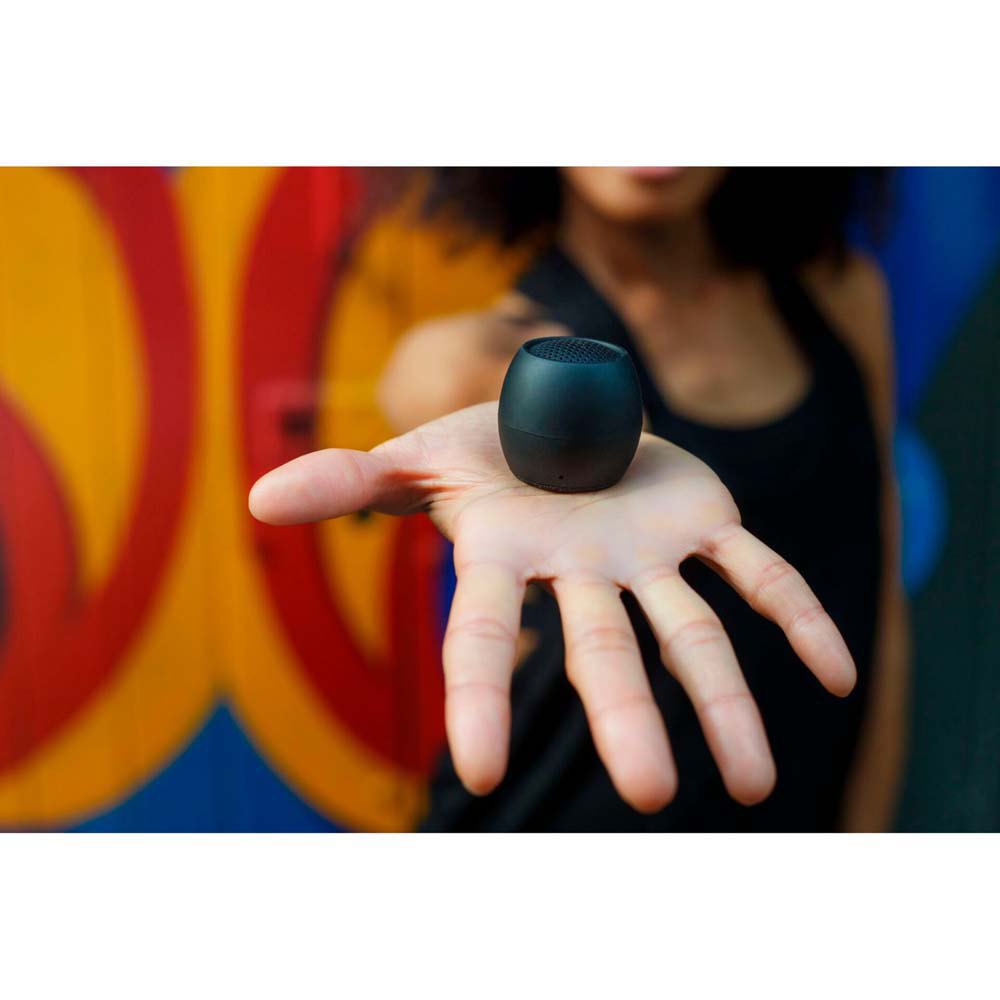 Blue mini wireless speaker held in a hand, compact round body and top grille