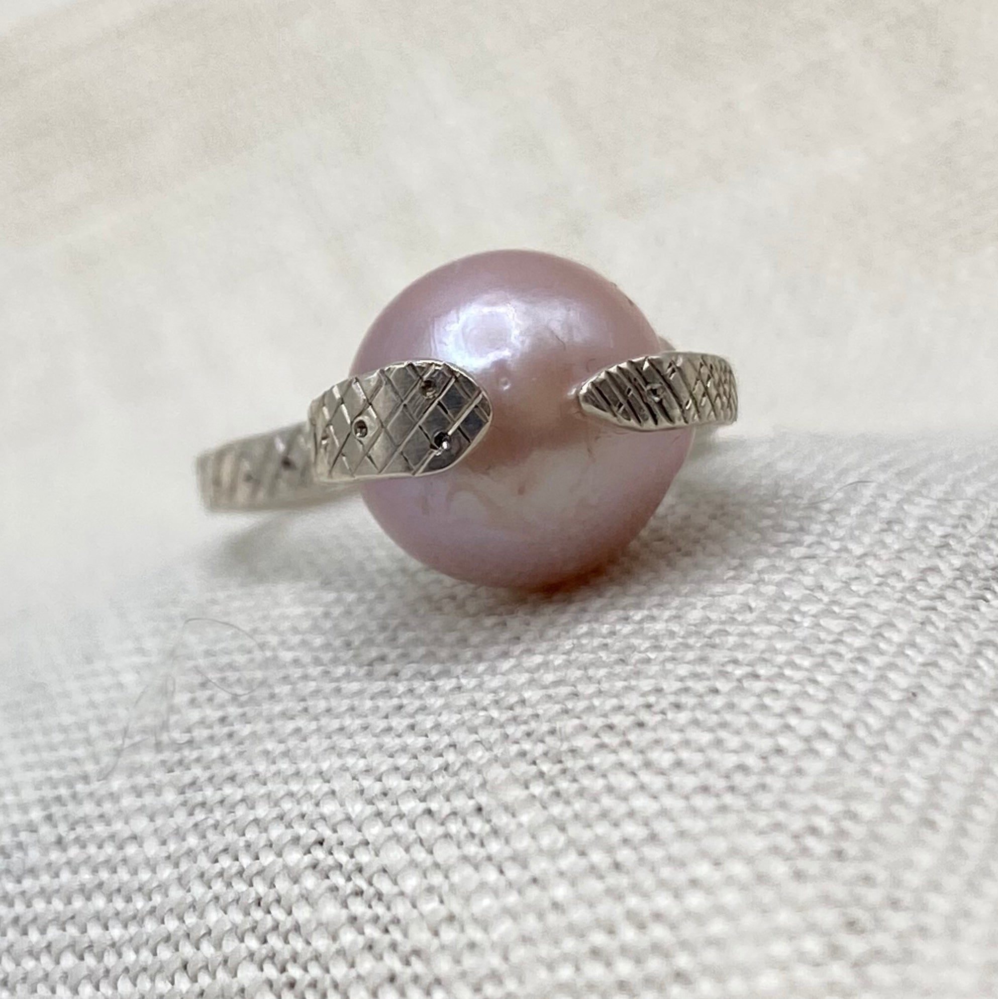 Sterling snake ring with blush pink pearl, side view with textured snake bands